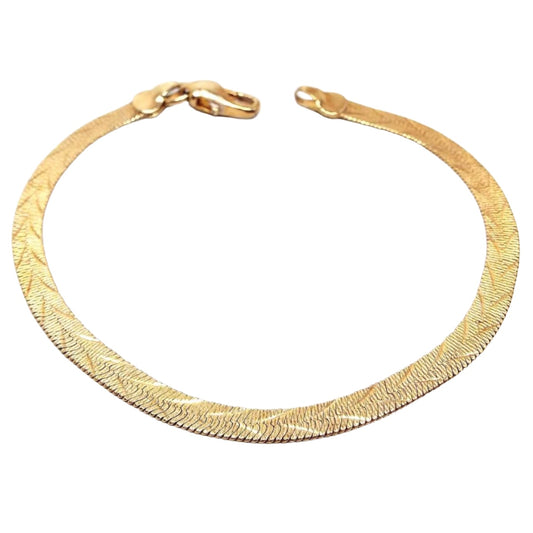 Top side view of the retro vintage reversible herringbone link chain bracelet. The metal is gold tone in color. This side has an etched V like pattern all the way down the bracelet. There is a lobster claw clasp on the end.