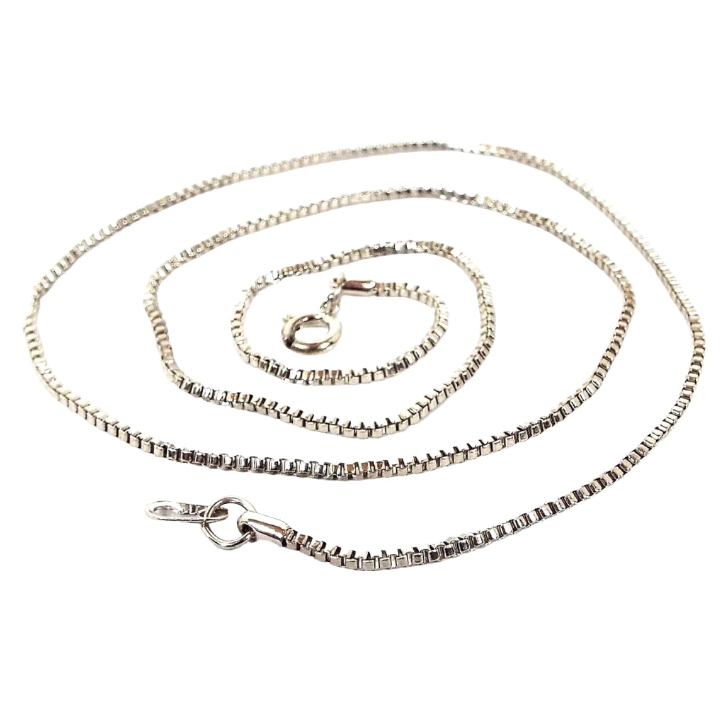 Top view of the retro vintage chain necklace. The metal is silver tone in color. It has a thin box chain link design with a round spring ring clasp on the end.