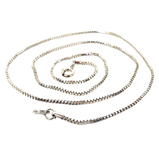 Top view of the retro vintage chain necklace. The metal is silver tone in color. It has a thin box chain link design with a round spring ring clasp on the end.