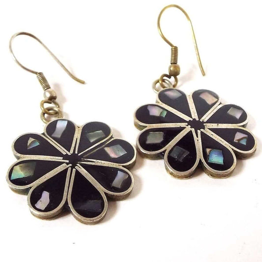 Front view of the retro vintage Mexican alpaca flower earrings. The metal is silver tone in color. The petals have black resin enamel and a piece of inlaid abalone shell at the end. The earwires are hook style.