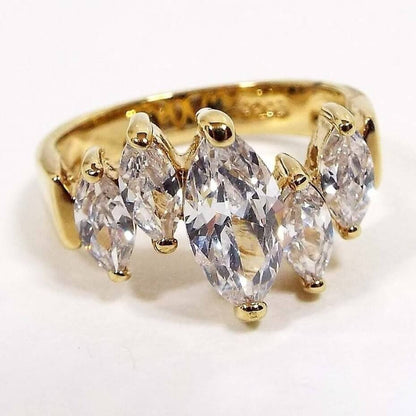 Front view of the retro vintage Edco cubic zirconia cocktail ring. The metal is gold tone in color. There are five prong set marquis cut CZ stones placed to make a slightly wavy appearance. The middle CZ stone is larger than the rest. The stamped marking for Edco is on the inside bottom of the band.