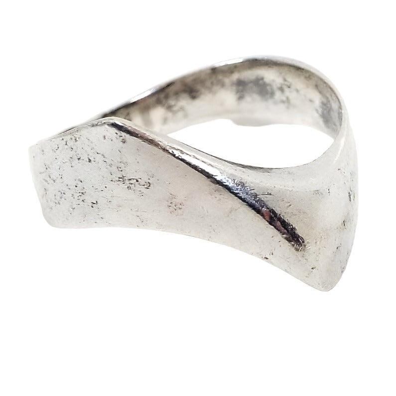 Angled front view of the retro vintage Polish sterling silver Modernist ring. The sterling is slightly darkened from age. Top of ring has a curved shape that curves outwards to form a sort of V like design. There are some darker areas on the inside of the band.