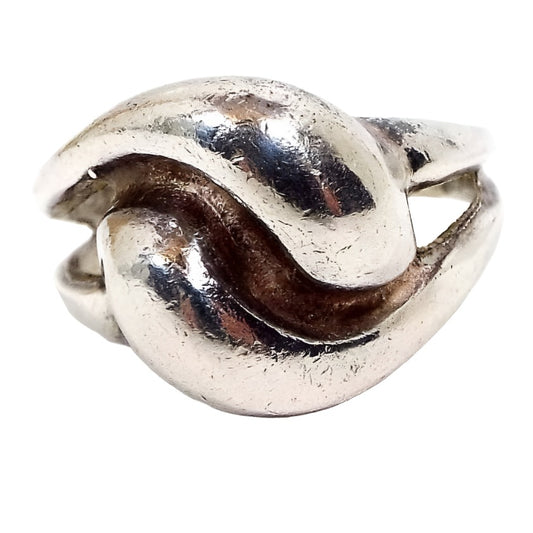 Angled front view of the retro vintage Polish sterling silver Modernist ring. The sterling is slightly darkened from age. Top of ring has two 3D style curved teardrop shapes that curl against one another for an almost knot like design. 