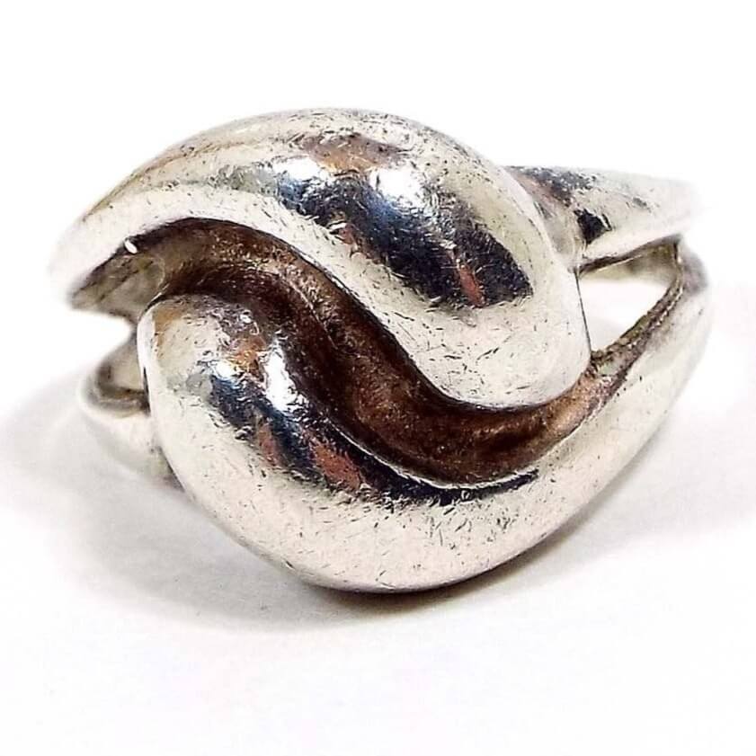 Angled front view of the retro vintage Polish sterling silver Modernist ring. The sterling is slightly darkened from age. Top of ring has two 3D style curved teardrop shapes that curl against one another for an almost knot like design. 