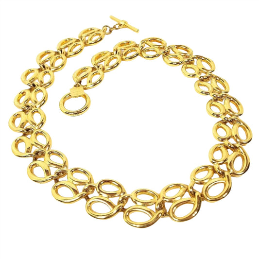 Top view of the retro vintage Anne Klein chain link necklace. It is gold tone in color. The links look like double open teardrops with a smaller one on the inside of the necklace and the larger on the outside. There is a toggle clasp at the end.