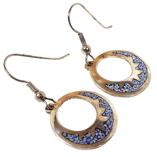 Front view of the small Mexican Alpaca vintage hoop earrings. They have an open circle design with the bottom part of the circle having a metal sun ray style design and inlaid tiny blue stone chips. The metal is silver tone in color. They have hook style earwires.