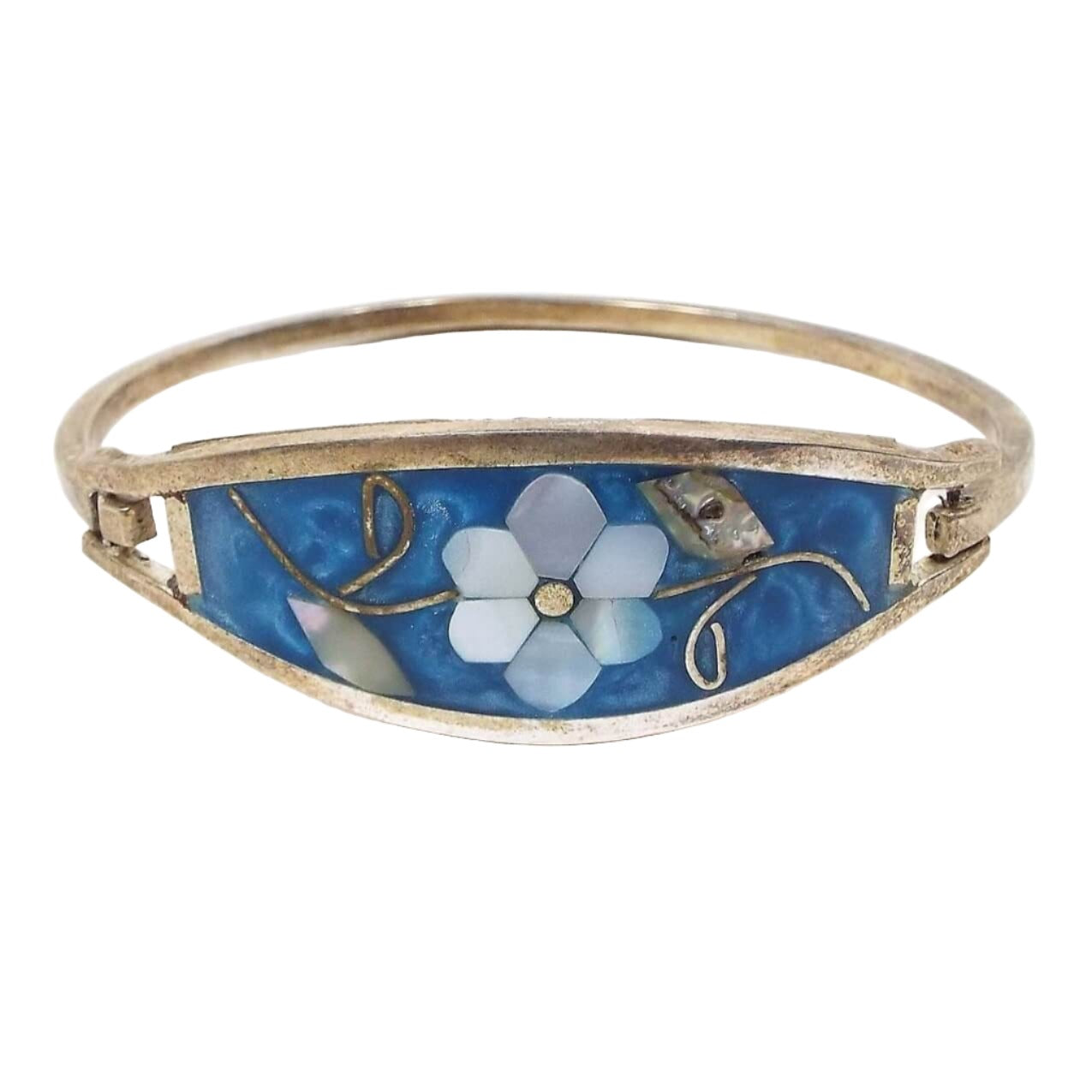 Front view of the Mexican Alpaca hinged bangle. It's silver in color with a curved metal band on the back and split double bands of metal on the front. In between is a curved shaped piece that has pearly blue resin. In the middle is a flower design with leaves and stem. The flower petals are mother of pearl shell and are pearly white color. The leaves are abalone shell and are pearly multi color. The stem is metal. One side has a metal hook style piece so you can open and close the bangle.  