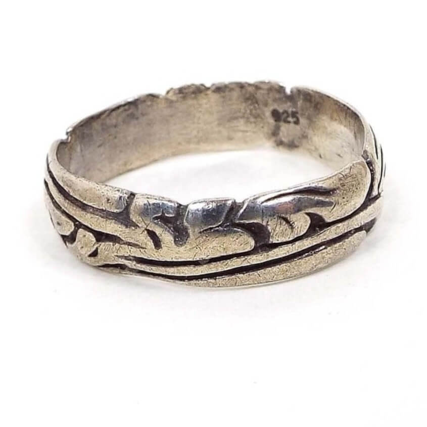 Side view of the retro vintage band ring. Ring is sterling silver with a smooth flat interior and a cut curvy leaf Art Nouveau style design all the way around the outside of the band. The ring is darker silver in color from age. 925 is stamped on the inside of the band.