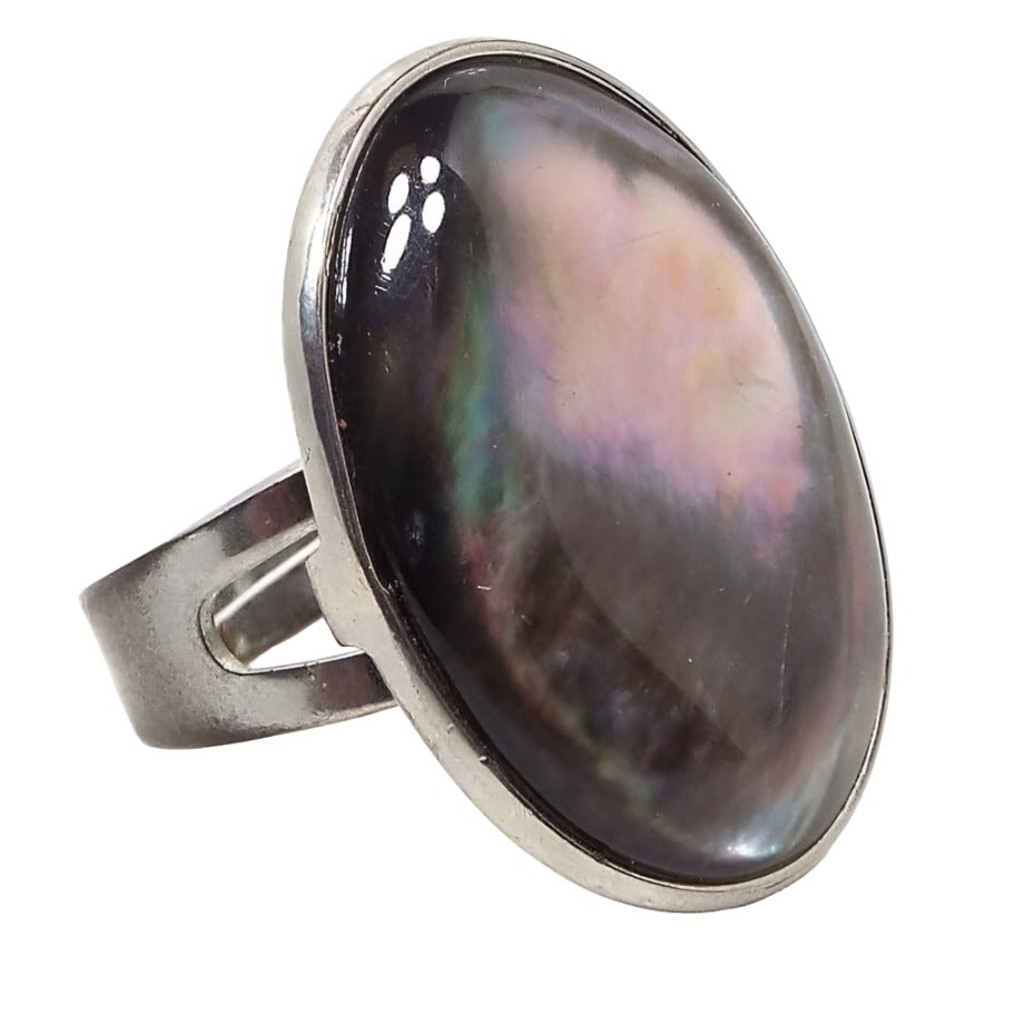 Front view of the retro vintage adjustable abalone Boho statement ring. The metal is silver tone in color. There is a large oval abalone shell cab on top that is bezel set. The band is flat curved and has a split style at the top. 