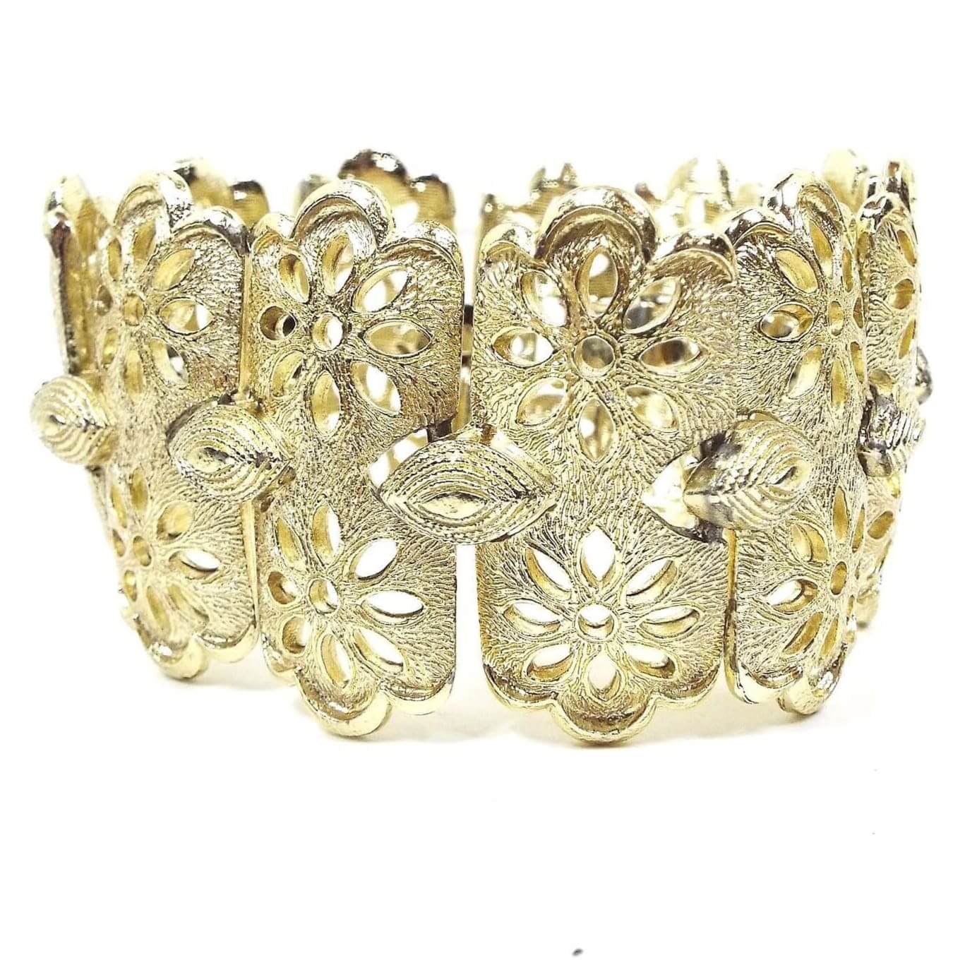Side view of the top of the Coro Pegasus filigree flower panel bracelet. It is gold tone in color with wide links. Each link has two side by side flower designs with cut out areas for the petals. 