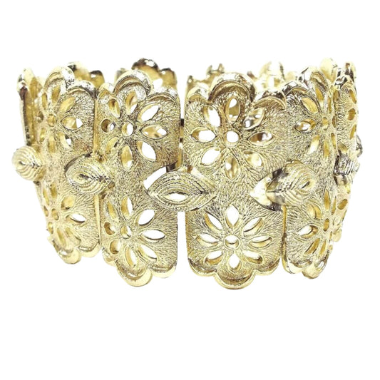 Side view of the top of the Coro Pegasus filigree flower panel bracelet. It is gold tone in color with wide links. Each link has two side by side flower designs with cut out areas for the petals. 