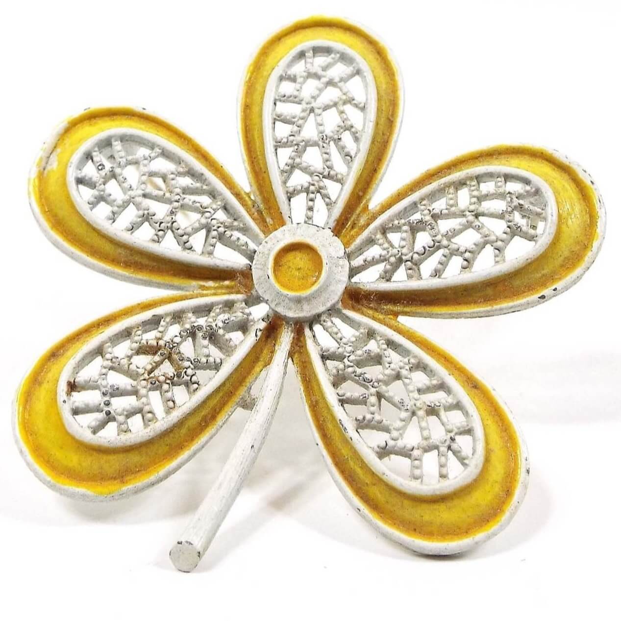 Front view of the 1960's Mid Century vintage Hippie flower brooch pin. It is shaped like a large flower with long rounded petals. The petals have a filigree design. It is white enameled with a yellow enamel edge and center. 
