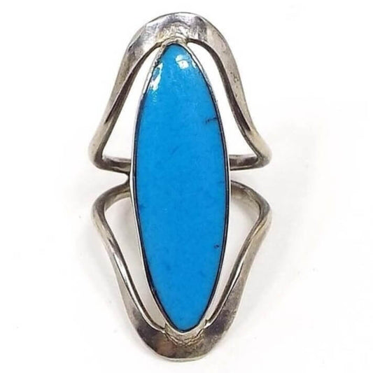 Front view of the retro vintage Mexican sterling silver imitation turquoise ring. The middle area is long marquis shaped with blue resin to look like turquoise. The sterling silver is slightly darkened in color. There is a band of metal that curves from the bottom and from the top of the resin front and they join together at the back to form the band.