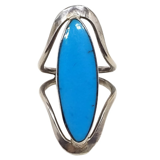 Front view of the retro vintage Mexican sterling silver imitation turquoise ring. The middle area is long marquis shaped with blue resin to look like turquoise. The sterling silver is slightly darkened in color. There is a band of metal that curves from the bottom and from the top of the resin front and they join together at the back to form the band.