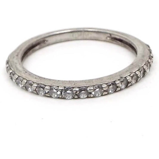 Angled top and side view of the retro vintage cubic zirconia band ring. It has small thin row of CZ stones that are prong set on the top and sides of the band.. The metal is darkened silver in color.