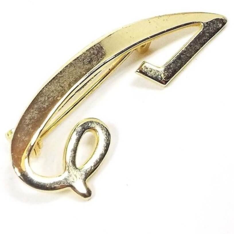 Front view of the Mid Century vintage letter brooch. The metal is gold tone in color. The brooch is a flat shaped fancy script initial I but also looks like it could be used for an initial C.