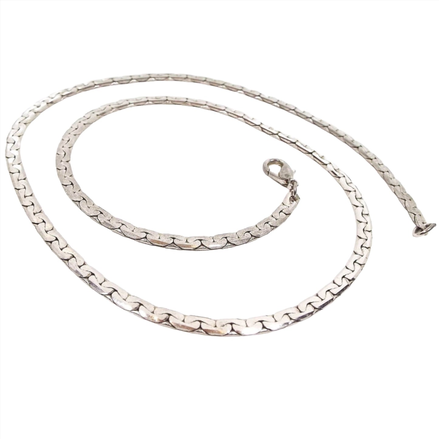 Chain necklace is silver in color and flat in style with interlocked rounded half moon shapes on each side. There is a lobster clasp on the end.