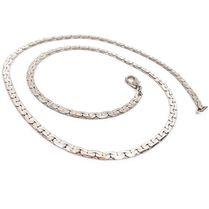 Chain necklace is silver in color and flat in style with interlocked rounded half moon shapes on each side. There is a lobster clasp on the end.